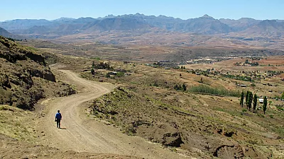 Un homme marche sur une route du col de Gates of Paradise près du village de Malealea dans les montagnes du Lesotho