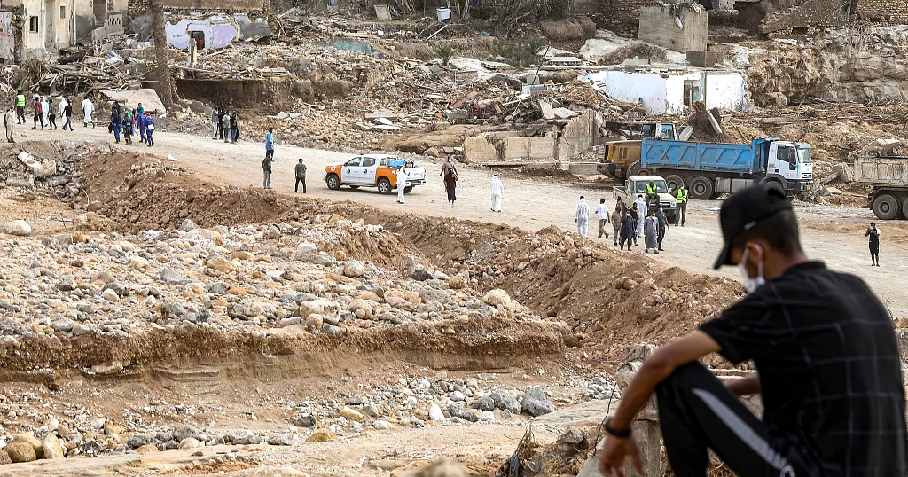 Un homme est assis tandis que les équipes de secours travaillent dans une zone détruite de la ville de Derna, dans l'est de la Libye, le 18 septembre 2023 - Copyright © africanews MAHMUD TURKIA/AFP or licensors