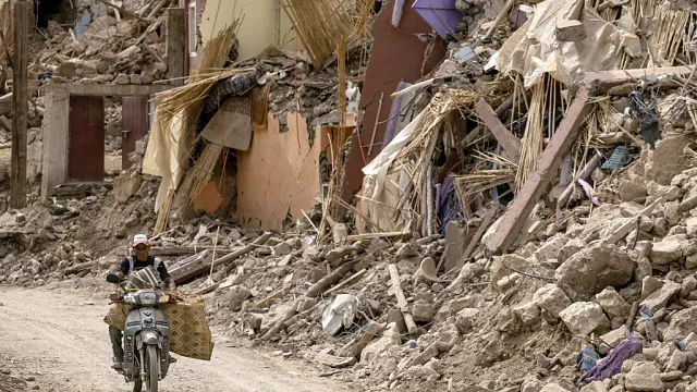 Un homme roule à moto à côté des décombres dans le village d'Imi N'Tala, frappé par le tremblement de terre, dans le centre du Maroc, le 5 octobre 2023. - Copyright © africanews FADEL SENNA/AFP or licensors